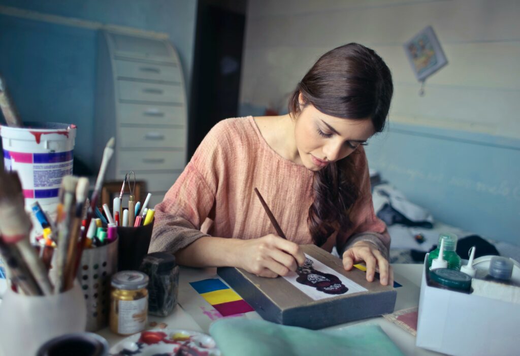 Female artist deeply engaged in painting at her creative studio workspace.